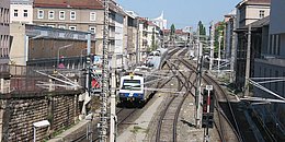 Zug der Wiener S-Bahn fährt zwischen Häuserzeilen.