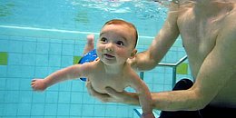 Baby mit Papa im Schwimmbad am Tauchen