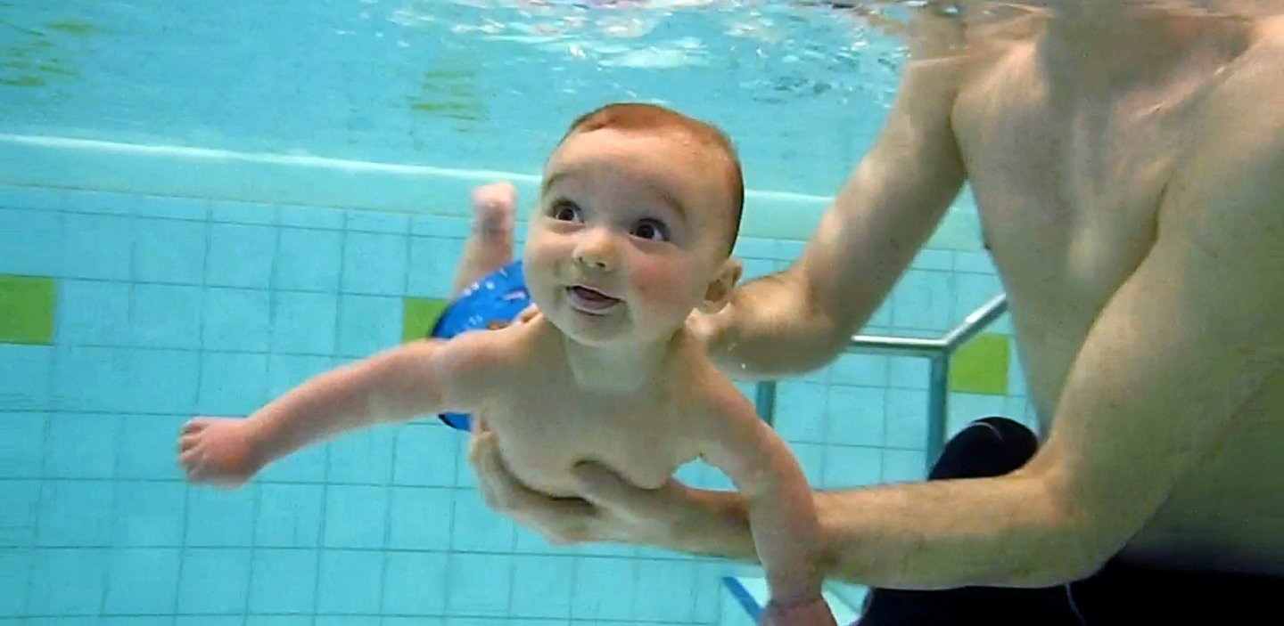 Baby mit Papa im Schwimmbad am Tauchen