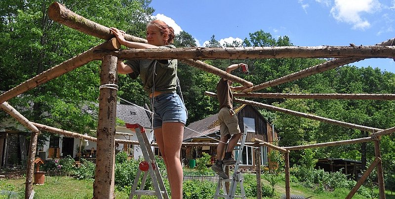 Zwei Personen bauen an einer Hütte aus Holz