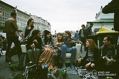 Junge Menschen sitzen zusammen am Naschmarkt