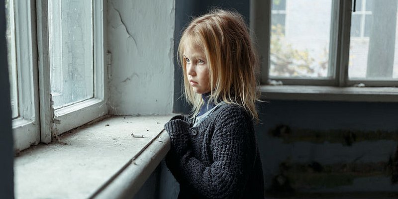 Armes Mädchen traurig aus dem Fenster blickend