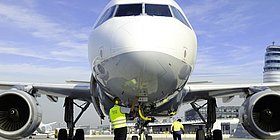 Detailansicht von einem Verkehrsflugzeug von Vorne mit 2 Arbeitern beim Flugzeug in Schutzweste