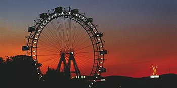 Bild von beleuchtetem Riesenrad bei Nacht.