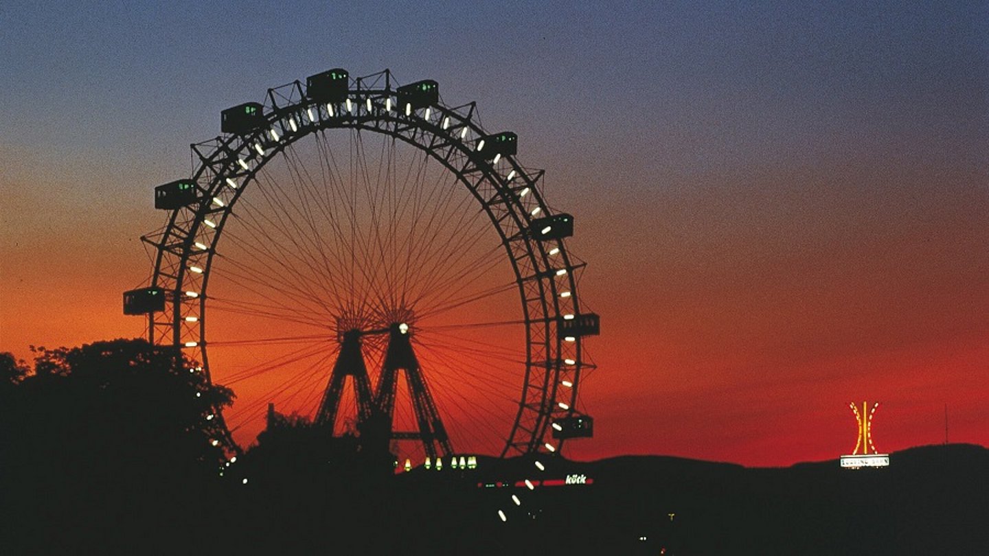 Bild von beleuchtetem Riesenrad bei Nacht.