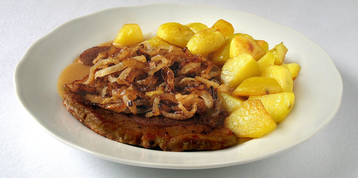 Altwiener Zwiebelrostbraten mit Braterdäpfel auf einem Teller angerichtet