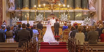 Brautpaar vor dem Traualtar auf den Kirchenbänken sitzen die Hochzeitsgäste