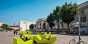 Grüne Enzis auf denen Menschen sitzen im Museumsquartier