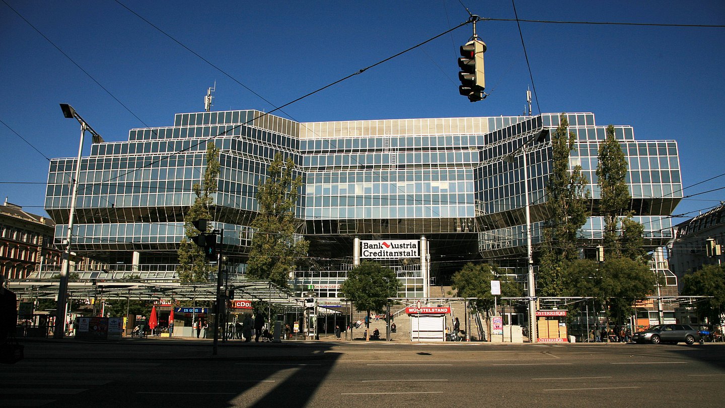 Vorderansicht des Bahnhofsgebäudes (Bank Austria-Gebäude). Am Bahnhofsvorplatz befinden sich Straßenbahnhaltestellen und Imbisbuden.