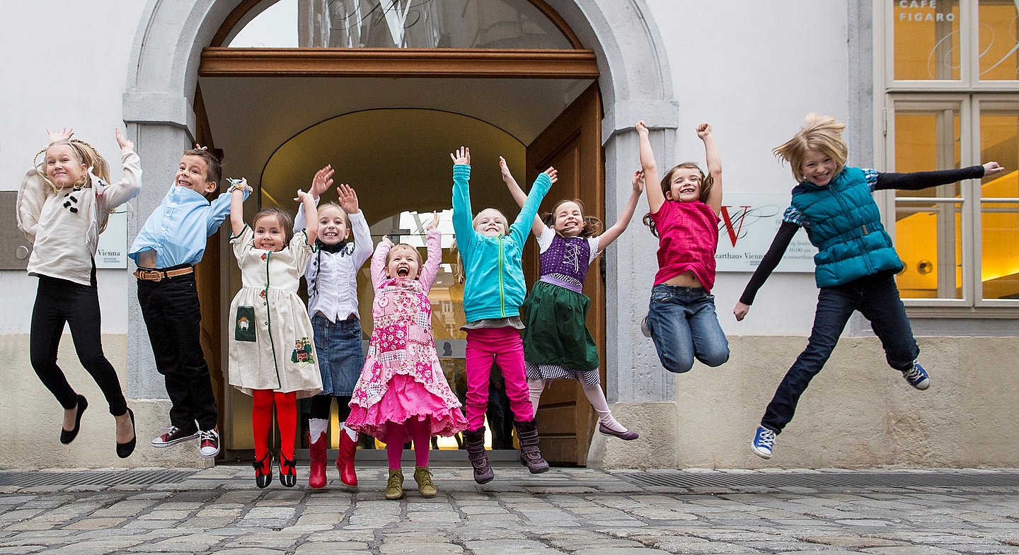 Kinder machen Luftsprünge vor dem Mozarthaus Vienna