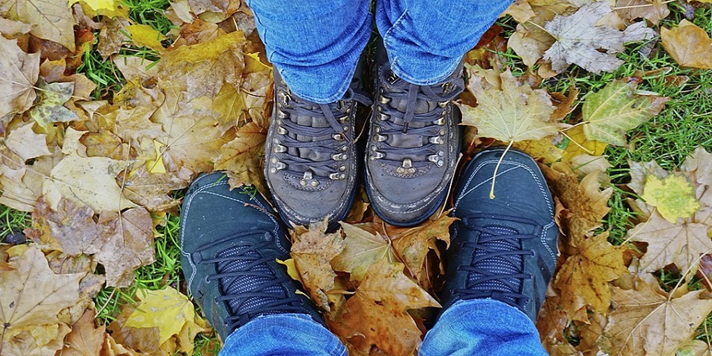 Menschen die Wanderschuhe tragen im Laub