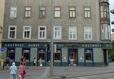 Sommerlich gekleidete Menschen auf der Straße vor dem Gasthaus