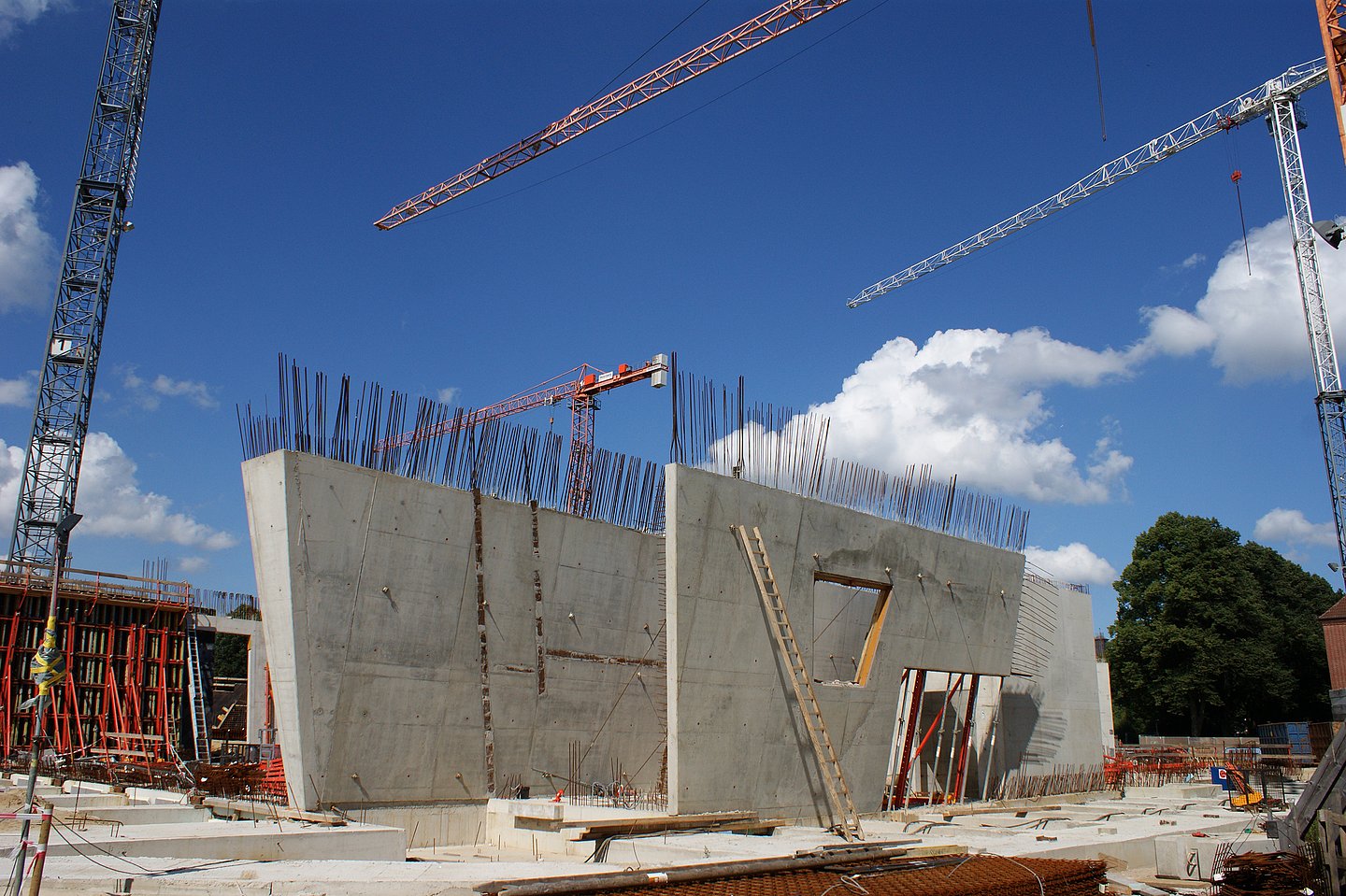 Krane bauen 2 Betonwände auf.