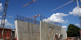 Krane bauen 2 Betonwände auf.