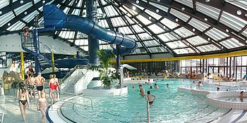 Seichter Eingang mit Treppe führt in ein kurviges Becken mit blauer Rutsche.