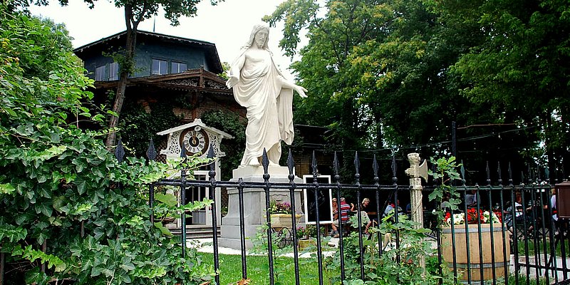 Christus Statue im Garten vor dem Schloss Concordia schräg vond er Seite über den Gusseisenzaun hinweg zu sehen