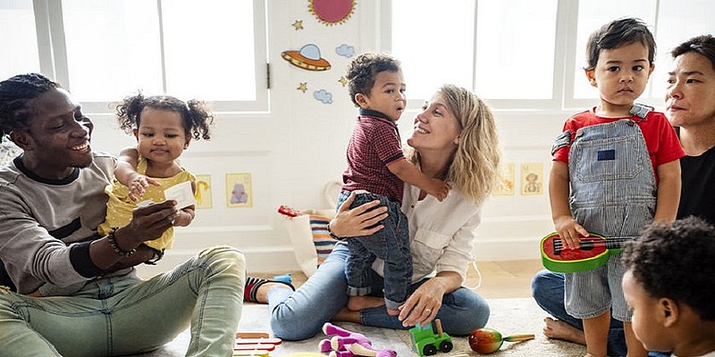 Kinder und ihre Eltern sitzen am Boden und spielen