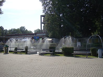 Eine größere betonierte Fläche, dahinter Wiese und Wiesensprenganlagen.