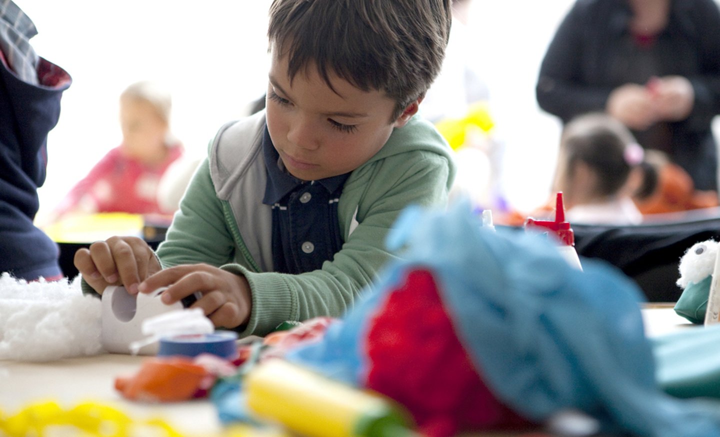 Ein Junge bastelt mit Wolle im Kinderatelier