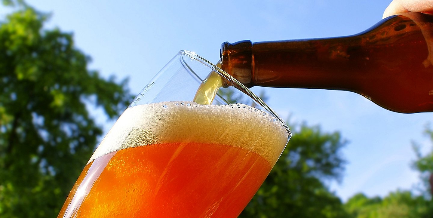 Bier, das aus einer Flasche in ein Glas gegossen wird 