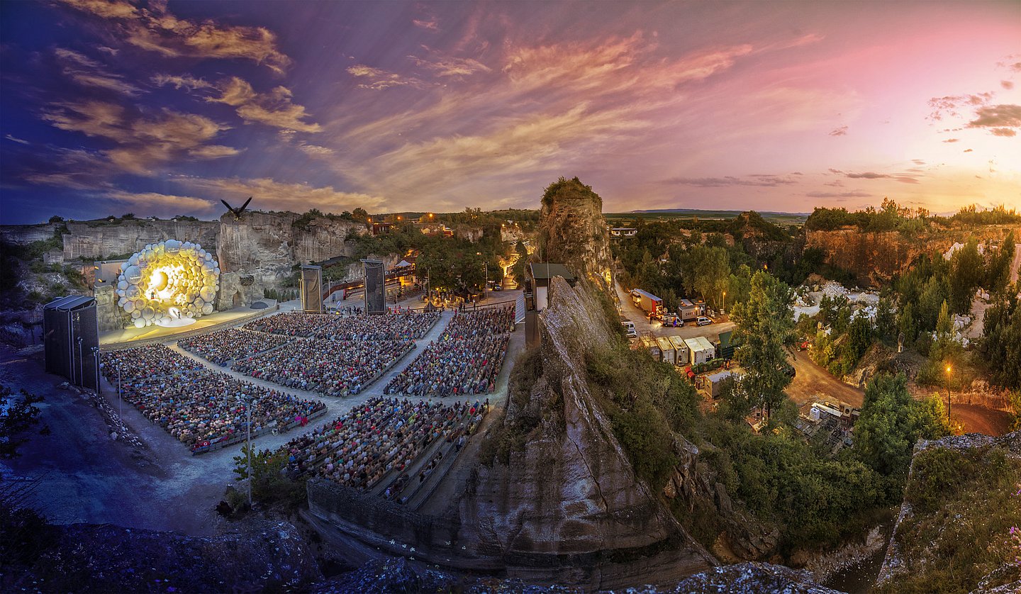 Römersteinbruch von oben in der Abenddämmerung, links die Bühne, im Hintergrund Sonnenuntergang