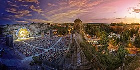 Römersteinbruch von oben in der Abenddämmerung, links die Bühne, im Hintergrund Sonnenuntergang