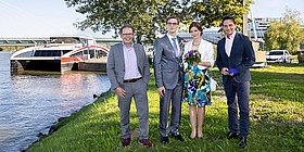 Hochzeitspaar steht im Grünen vor Schiff