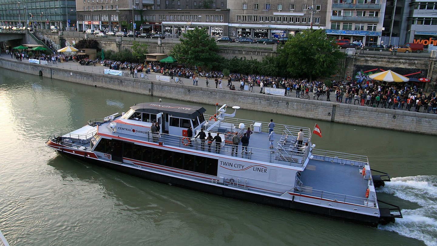 Ein Twin City Liner fährt gerade entlang des Donaukanals in Wien.