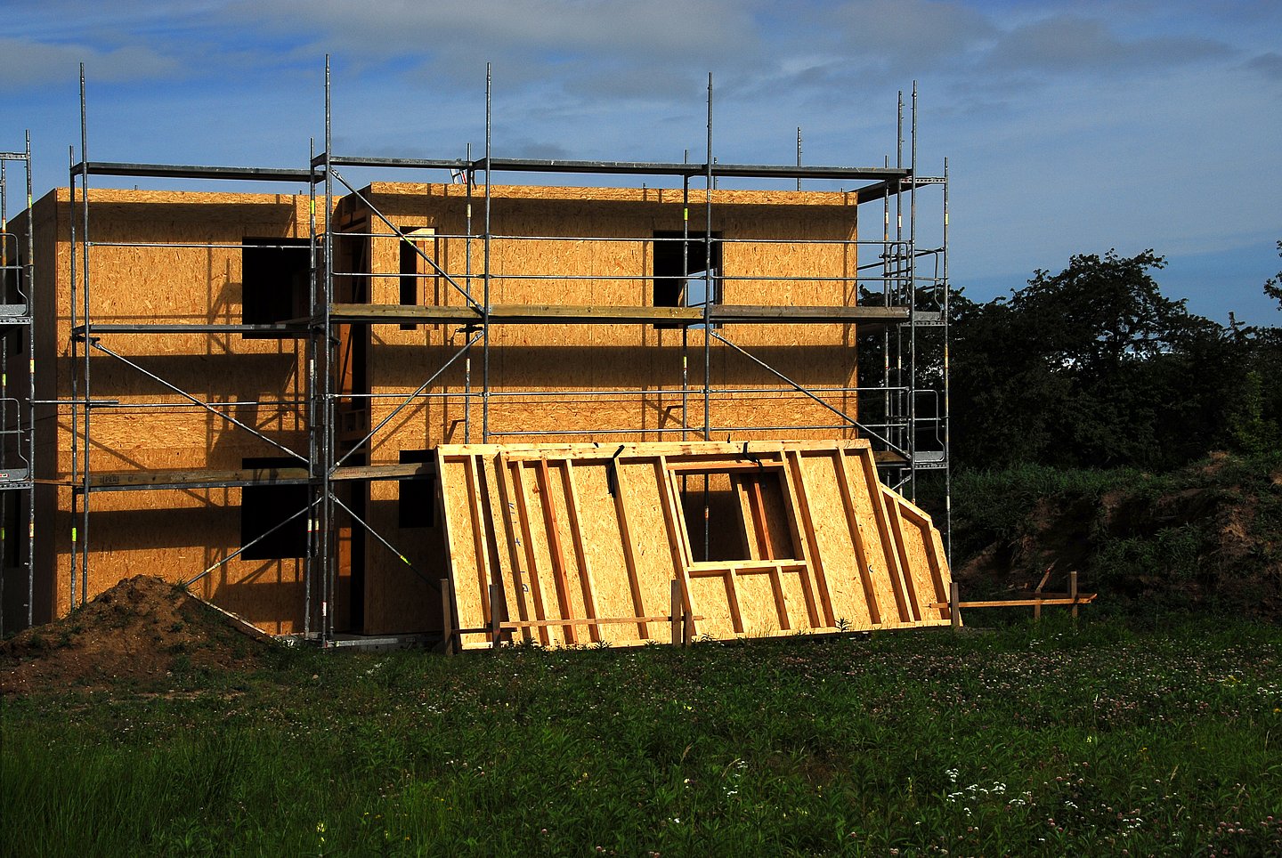 Niedrigenergiehaus im Rohbau mit Gerüst und Fertigteilwand aus Holz angelehnt