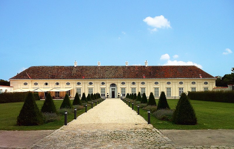 Ein helles Gebäude hinter einem kunstvollen Vorgarten