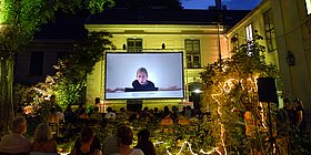 Menschen sitzen im Freien und schauen sich einen Film an.