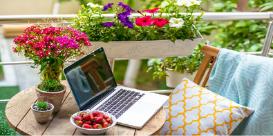 Balkon mit Blumenkiste und Laptop