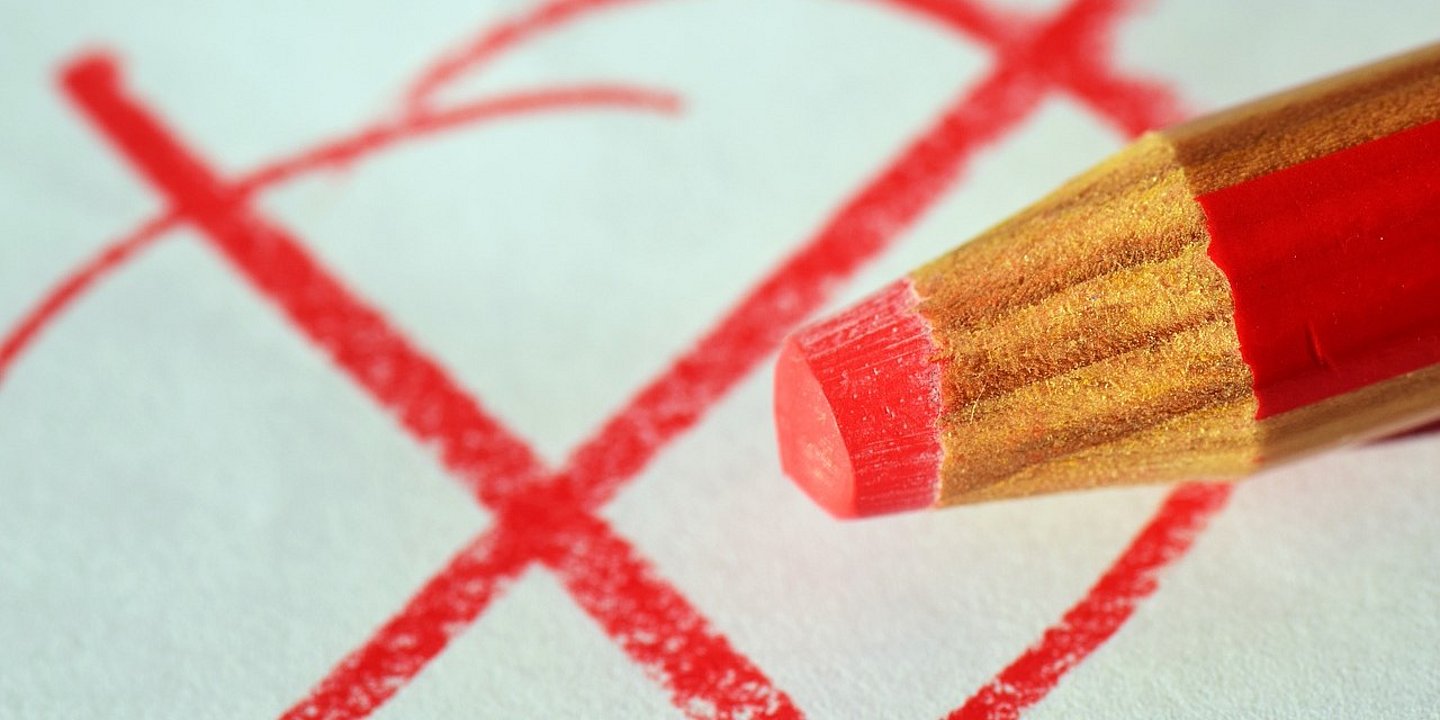 Roter Stift macht ein Kreuz