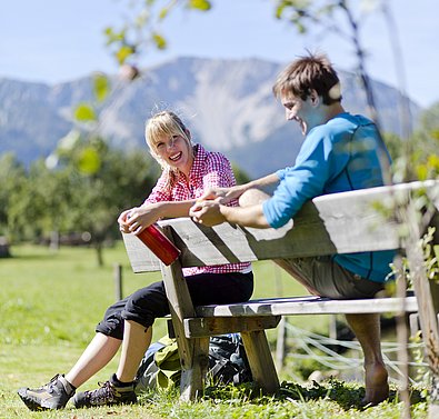 Mann und Frau auf einer Rastbank am Schneeberg bei Sommerwetter