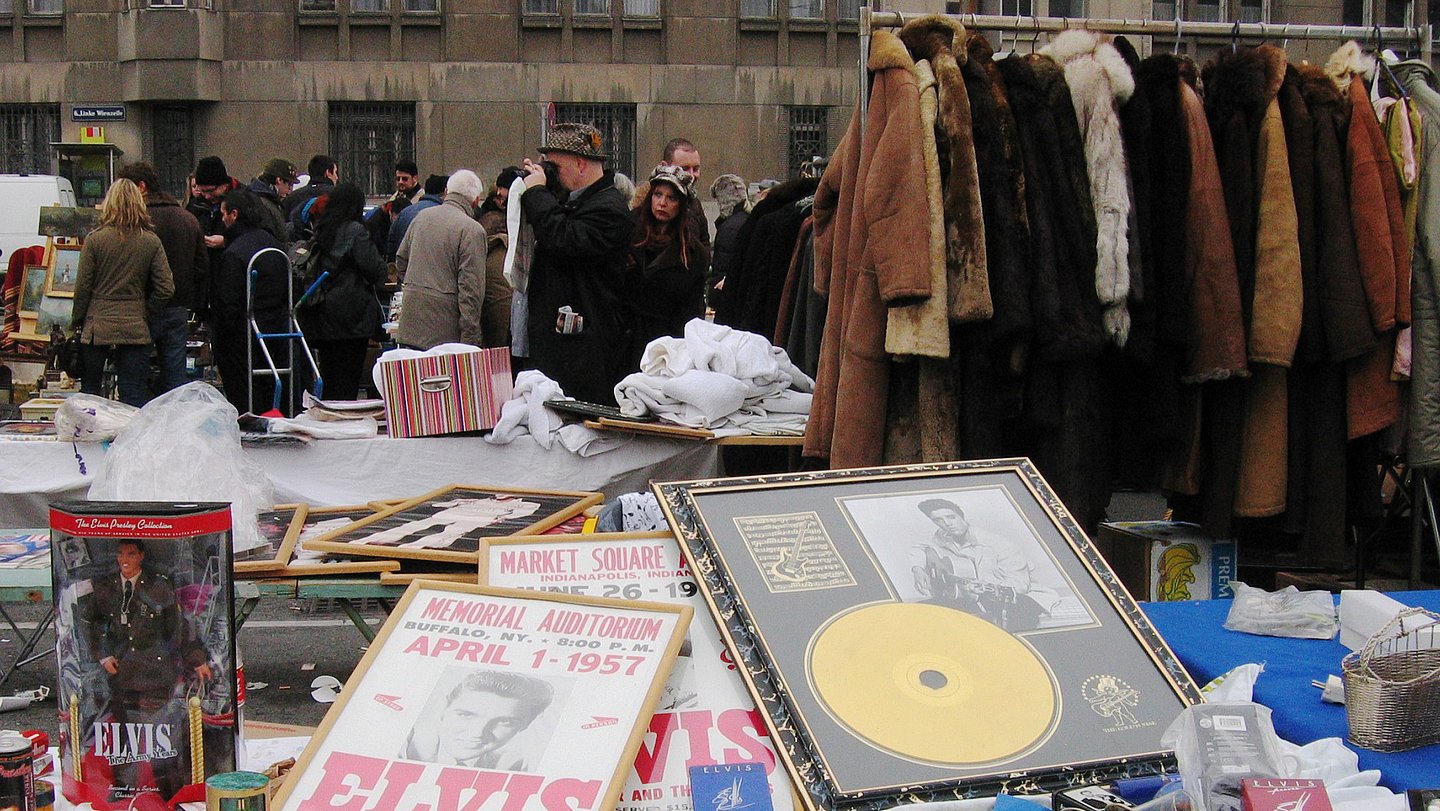 Bild von Verkaufsstand am Flohmarkt beim Naschmarkt. Angeboten werden Pelzmäntel, Elvis-Merchandise-Artikel und diverser Krims-Krams.