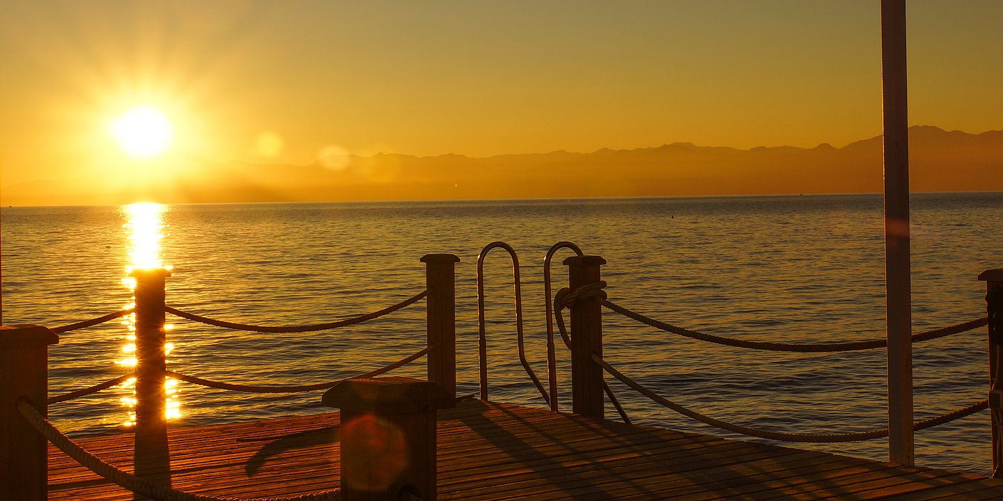 Sonnenuntergang mit einem Steg am Meer im Vordergrund