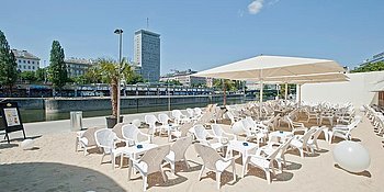 Strandterasse mit vielen Stühlen und Sonnenschirmen an einem schönen Tag am Donaukanal