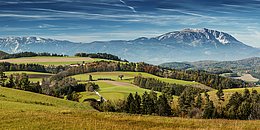 Berg ragt hinter Hügellandschaft in der buckligen Welt empor.