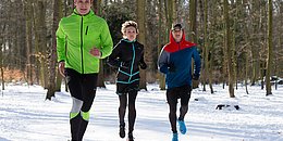 3 sportliche Läufer im Schnee